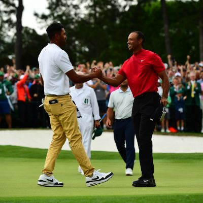 Tony Finau and Tiger Woods can be seen shaking hands as the crowd is cheering on.